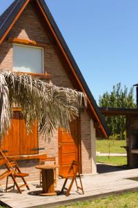 una cabaña con sillas y una mesa frente a ella en Cabañas La Esperanza en Tornquist