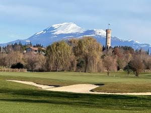 a golf course with a snow covered mountain in the background at Appartamento Stella in Pozzolengo