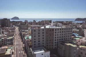 an aerial view of a city with buildings and the ocean at Kenny Stay Jeju Seogwipo in Seogwipo