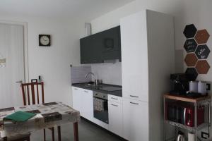 une cuisine avec des armoires blanches, une table et une cuisinière dans l'établissement Cà Maurizio garden Venezia, à Marghera 6 autres photos