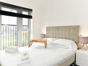 a white bedroom with a large bed and a window at Pass the Keys Sleek 1 Bed Apartment w Parking in Cardiff