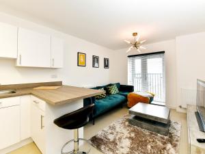 eine Küche und ein Wohnzimmer mit einem grünen Sofa in der Unterkunft Pass the Keys Sleek 1 Bed Apartment w Parking in Cardiff