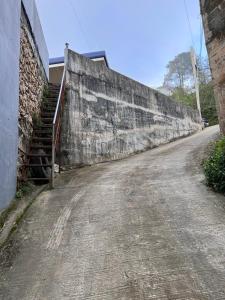 an empty road next to a stone wall at THE GRAY AURORA in Baguio