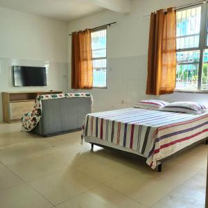 1 dormitorio con cama, sofá y TV en Apt melhor localização da Barra, en Salvador