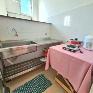 una mesa rosa en una cocina con fregadero en Apt melhor localização da Barra, en Salvador