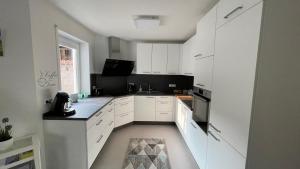 eine weiße Küche mit weißen Schränken und einem Fenster in der Unterkunft Ferienwohnung Eden in Mellrichstadt