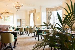 a restaurant with tables and chairs and plants at Glenesk Hotel in Edzell