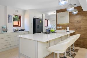 eine Küche mit weißen Schränken und einer weißen Arbeitsplatte in der Unterkunft Luxurious Modern Villa at Upmarket Golf and Beach Estate in Marina Beach