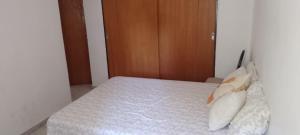 1 dormitorio con 1 cama con sábanas y almohadas blancas en DEPARTAMENTO 1 en Córdoba