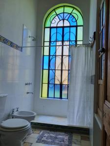 a bathroom with a toilet and a stained glass window at Inocencia Faez in Roldán