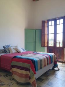Un dormitorio con una cama con una manta de colores. en Inocencia Faez en Roldán
