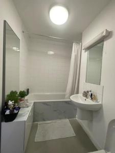 La salle de bains blanche est pourvue d'un lavabo et d'une baignoire. dans l'établissement Spacious one bedroom ft in Central London King’s Cross, à Londres