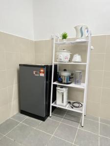 a small kitchen with a shelf next to a refrigerator at Naufa Muslim's Homestay at Emerald Avenue Brinchang in Brinchang +14 photos