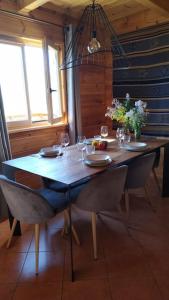 uma mesa de madeira com cadeiras e copos de vinho em Grand chalet en bois avec vue splendide em Le Dévoluy