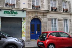 a red car parked in front of a building with a blue door at Warm 18m ideal for couple in Paris in Paris