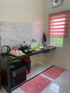 a kitchen with a counter with pink rugs at Hana Homestay in Pendang