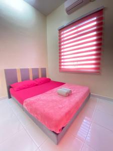 a bedroom with a pink bed with a window at Hana Homestay in Pendang