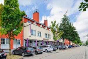 una fila di auto parcheggiate di fronte a un edificio di PLAZA INN Regensburg a Ratisbona