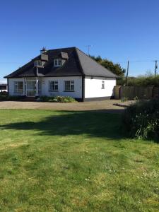 a white house with a large yard at Padua Guest Accommodation Rosslare in Rosslare