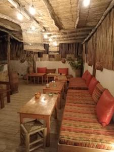 Habitación con mesas de madera y bancos en un edificio en Riad Le Khan Mogador en Essaouira