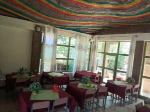 uma sala de jantar com mesas e cadeiras vermelhas e janelas em Lalibela Hotel em Lalibela