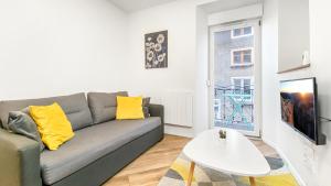uma sala de estar com um sofá cinzento e almofadas amarelas em HOMEY WALTER - Proche Gare - Balcon privé - Wifi em La Roche-sur-Foron