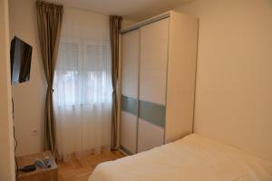 ProkupljeにあるApartmani TEOのベッドルーム1室(ベッド1台付)、窓付きのキャビネットが備わります。