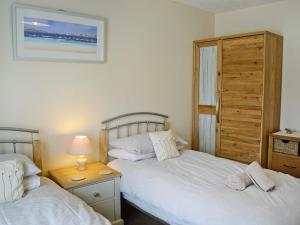 a bedroom with two beds and a table with a lamp at Chynoweth in Saint Merryn
