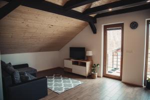 a living room with a couch and a television at Tree&Water Apartament nad jeziorem Ublik in Ublik