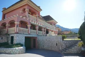 a large pink building with a balcony on a stone wall at TESS Villa Cari in Alhaurín de la Torre