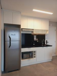 a kitchen with a stainless steel refrigerator and white cabinets at Cityhome Platina Tatuapé in Sao Paulo