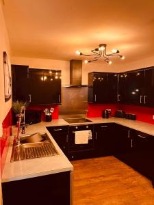 een keuken met zwarte kasten en een wastafel bij 'Woodbury' at stayBOOM in Lancaster
