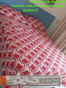 a bed with a red and white pattern on it at Apartamento a 60 metros para pé na areia - The Fountains - apto 105 in Beberibe