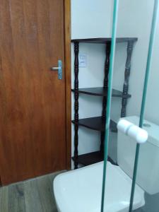 ein Badezimmer mit einem WC und einer Holztür in der Unterkunft Apartamento em chácara com piscina próximo de praias com internet in São Francisco do Sul