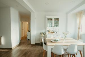 a white dining room with a table and chairs at Apartamento turístico Cedeira Casa Bustabad in Cedeira