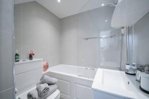 La salle de bains blanche est pourvue d'une douche et d'un lavabo. dans l'établissement Beautiful 2 Bedroom House With Spacious Garden BBQ, à Brasted