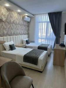 um quarto de hotel com duas camas e uma cadeira em Ulug`bek Grand Hotel em Samarkand