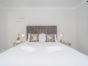 a white bedroom with a large white bed with pillows at Luxury 2Bed 2Bath Flat in City Centre- Free Parking! in Edinburgh