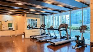 a gym with several tread machines in a room with a pool at 2 Bedroom apartment on Central Park Mall in Jakarta