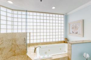 a bathroom with a tub and a glass shower at Sterling Sands 614 in Destin