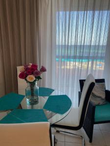 a dining room table with a vase of flowers on it at Alojamiento con balcon hacia la playa 115 in Miami Beach