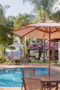 a table with an umbrella next to a swimming pool at Pousada Rávis - Café e Descanso in Sabará