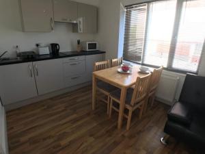 a kitchen with a wooden table and chairs in a kitchen at City Sparrow Apartment 6c in London