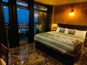1 dormitorio con 1 cama y balcón con vistas. en Hotel Acropolis, en Shillong