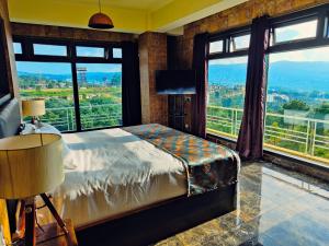 sypialnia z łóżkiem i dużymi oknami z widokiem w obiekcie Hotel Acropolis w mieście Shillong