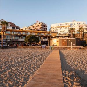 una pasarela de madera en una playa de arena con edificios en RentOnTheBeach Studio 2 en Los Cristianos