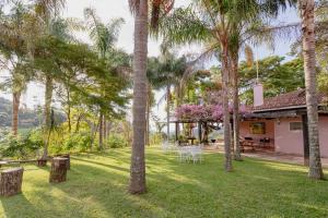 a yard with palm trees and a house with a table and chairs at Pousada Rávis - Café e Descanso in Sabará