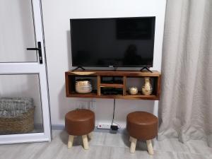 a television on a wooden entertainment center with two stools at Chef's@6 in Springbok