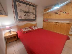um pequeno quarto com uma cama vermelha e uma mesa em Appartement Samoëns, 3 pièces, 4 personnes - FR-1-624-73 em Samoëns