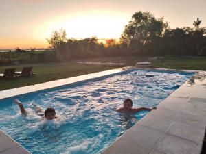 two people are swimming in a swimming pool at Yporá Lodge in Colonia Carlos Pellegrini